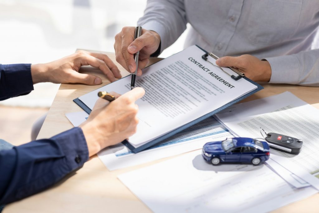 Car Insurance document or lease concept the car broker assisting his customer and explaining the